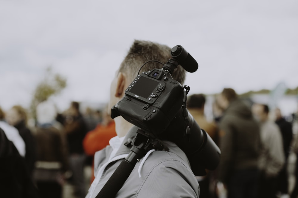 man with black DSLR camera on his shoulder