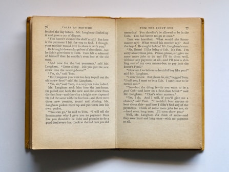 An open book is displayed showing two pages filled with text. The left page is numbered 76 and the right page 77. The text appears to be part of a story titled 'Tales at Bedtime'. The pages have a slightly aged appearance, with yellowing paper and dark text. The book is lying on a flat surface, and its cover is visible along the left edge.