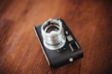 Soft focus image of a vintage camera resting on a wooden table near a window.