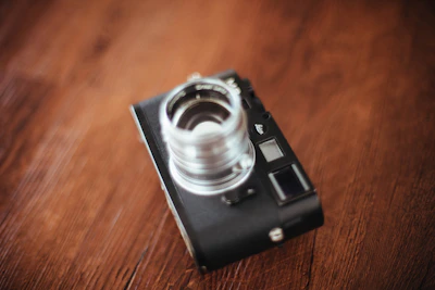 Soft-focus image of a vintage camera on a rustic wooden table.