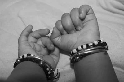 Hand holding a set of delicate beaded bracelets with soft pink and cream tones.