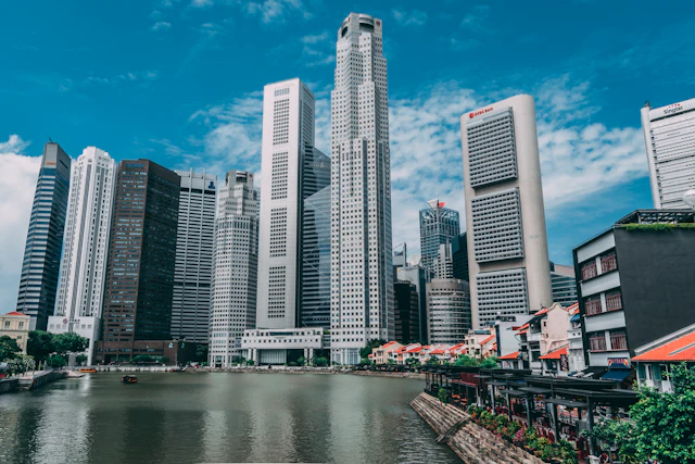 Boat Quay's riverside shophouses below the CBD towers, blue sky