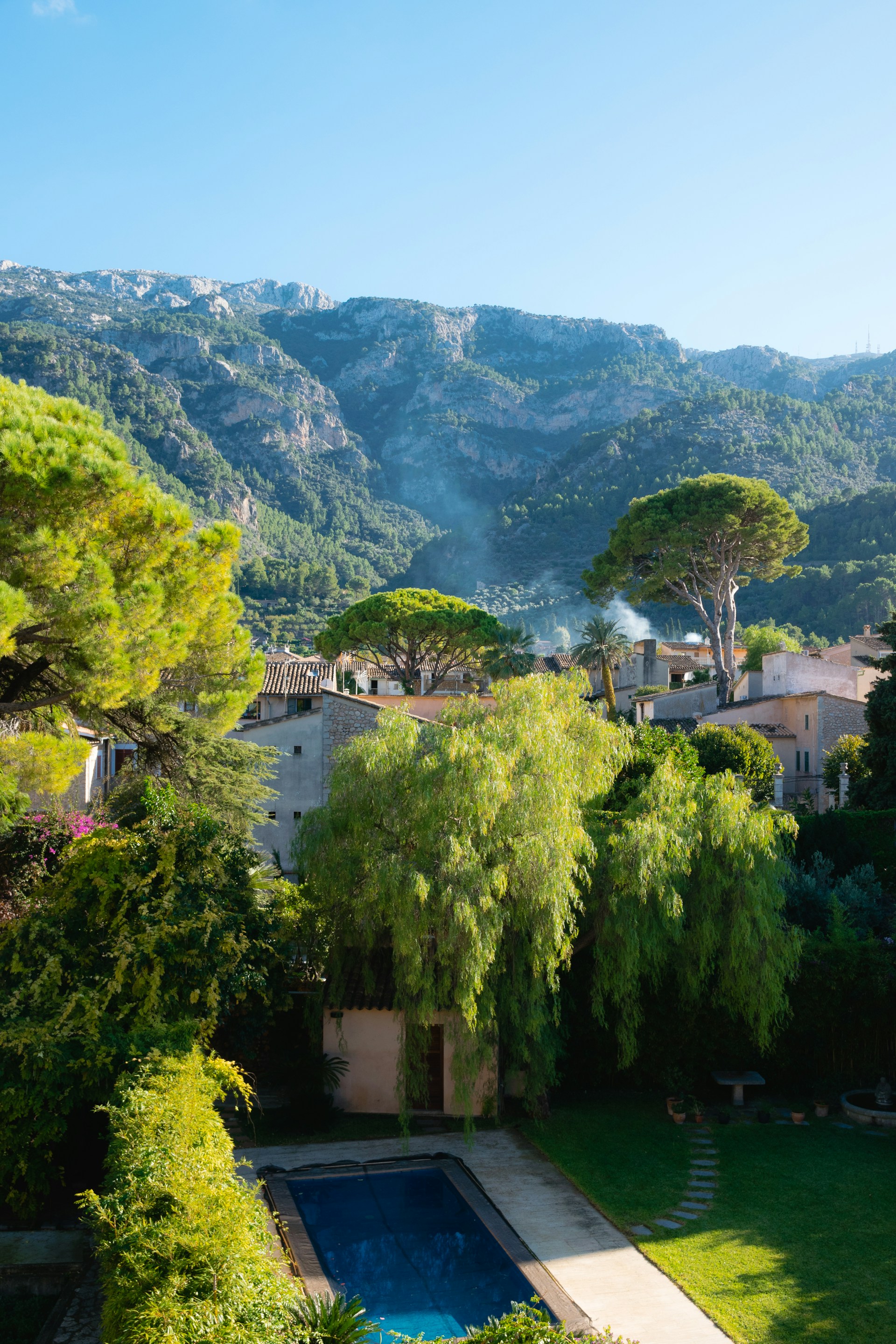 A serene view of a luxurious villa surrounded by lush greenery and a clear blue sky.
