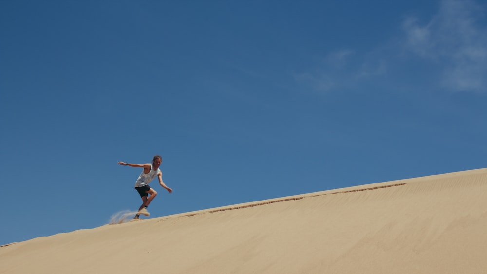 青空の下、茶色の砂の上を走る男