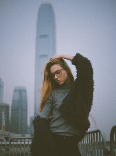 A sleek model wearing a chic, minimalist jasmin urban outfit against a cityscape backdrop at dusk.