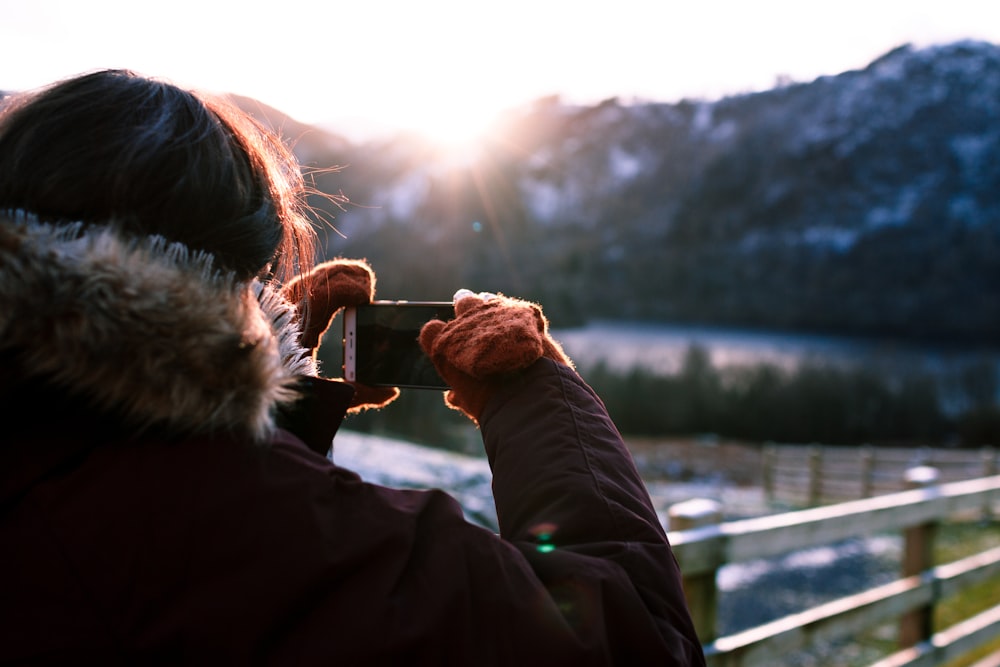 Persona con parka sosteniendo el teléfono tomando una foto