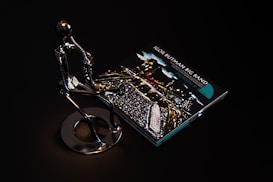 A sleek metallic sculpture of a person playing a saxophone is positioned beside a CD case featuring album art for 'Igor Butman Big Band.' The setting is dark, highlighting the reflective surface of the sculpture and the vibrant colors of the CD cover art.