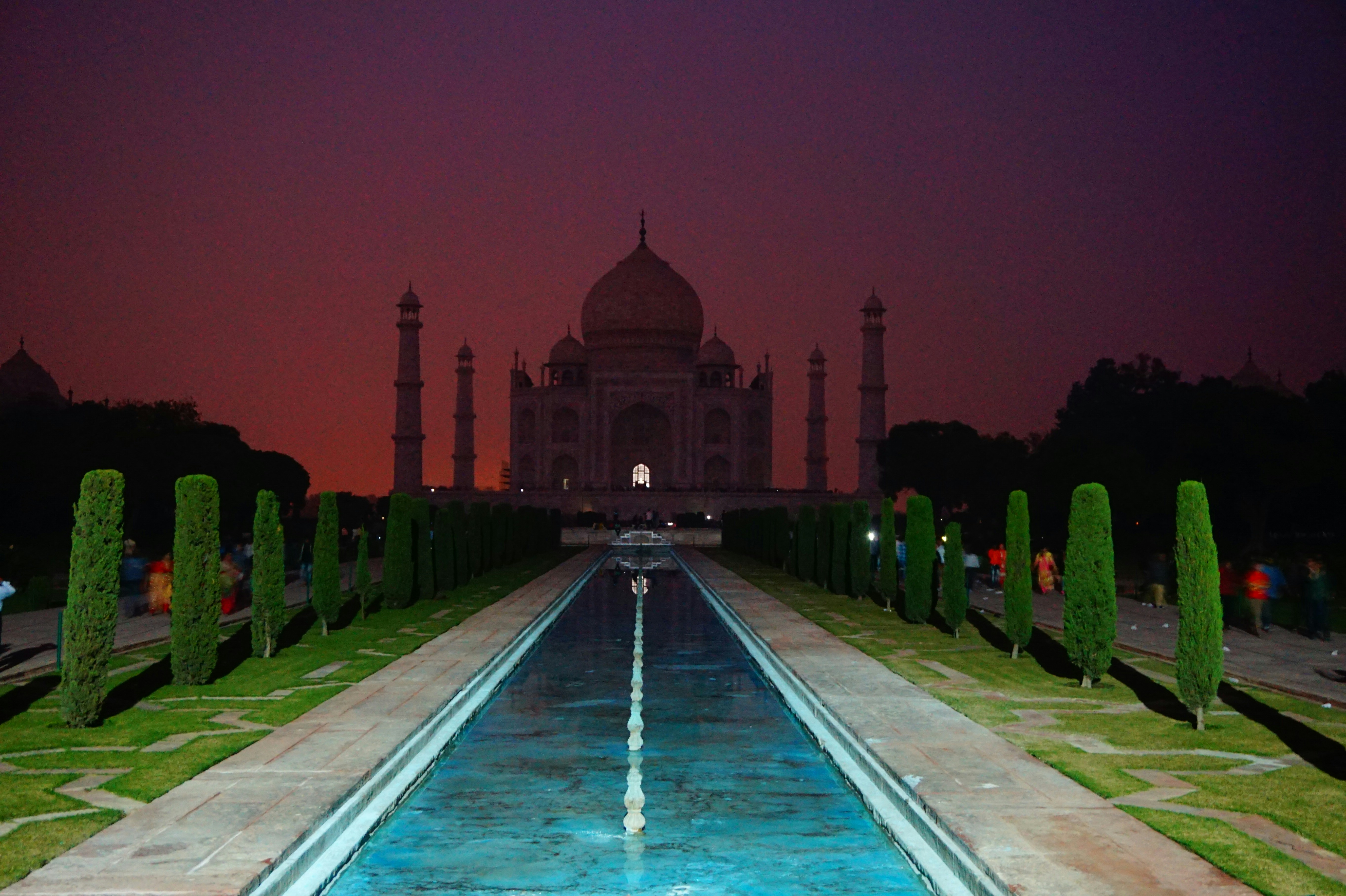 Taj Mahal at dawn with mist over reflecting pool, dark silhouetted gardens, moody atmospheric low-light