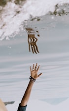 person's hand reaching on water with reflection ]