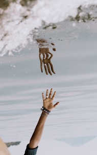 person's hand reaching on water with reflection ]
