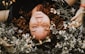 woman lying on flowers during daytime