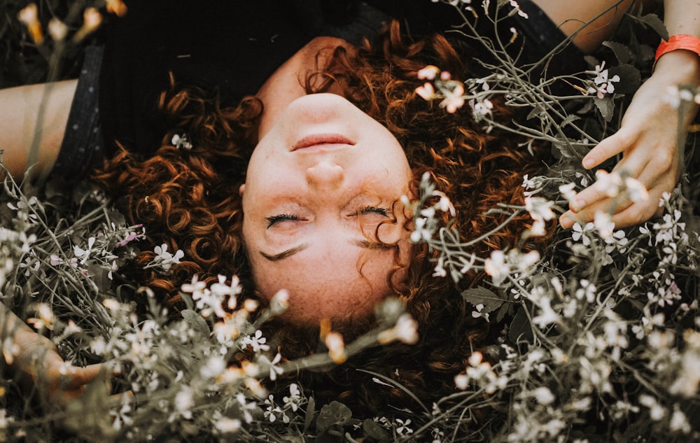 woman lying on flowers during daytime