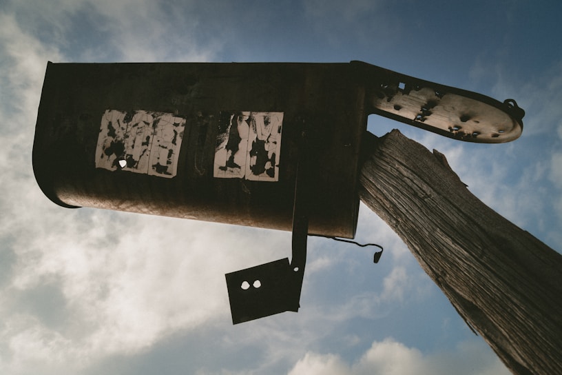 A close-up of a worn-out, rusty trailer mailbox plastered with 'The Trailer Parkerz' stickers.