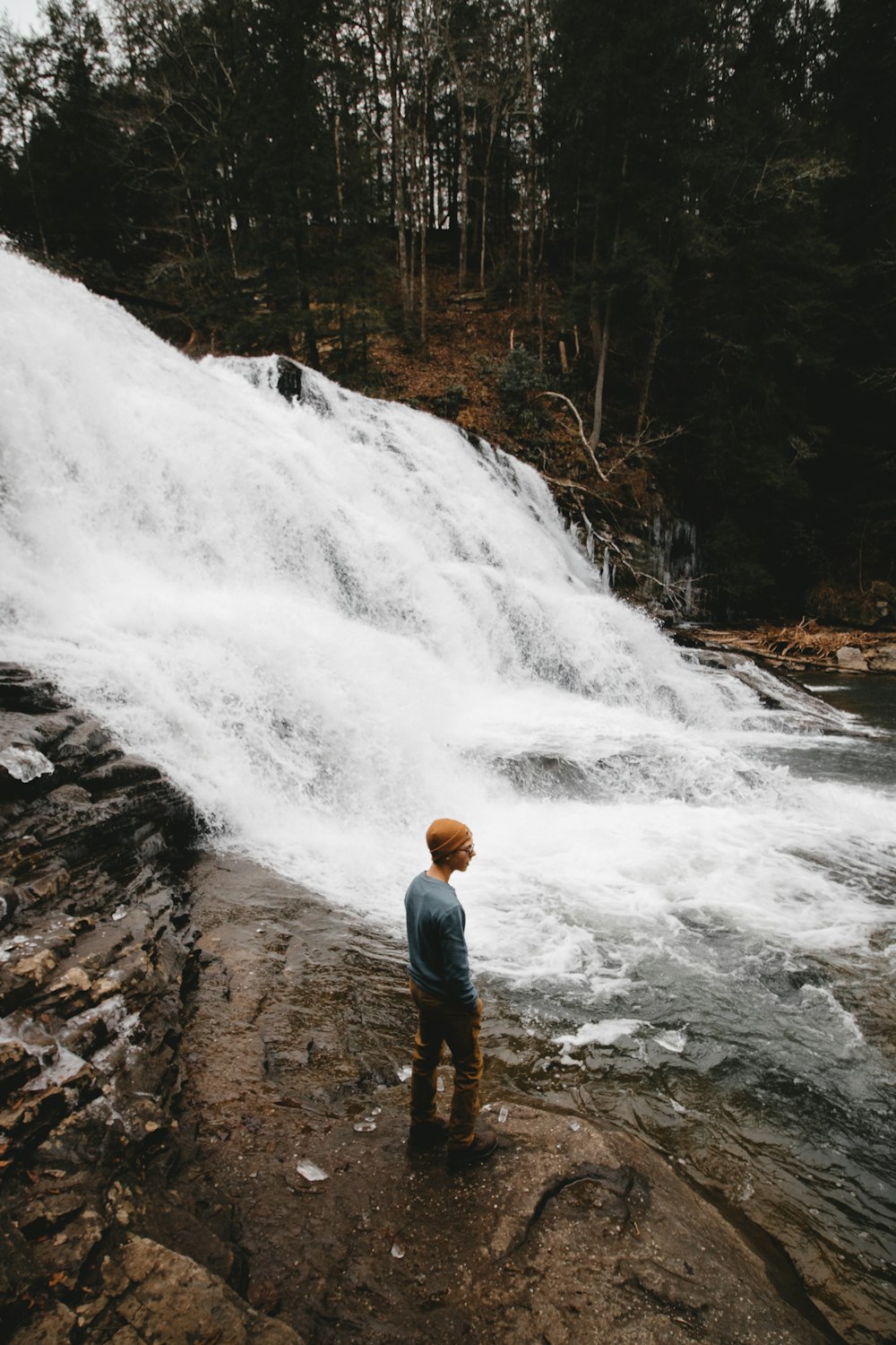 man standing near water falls
