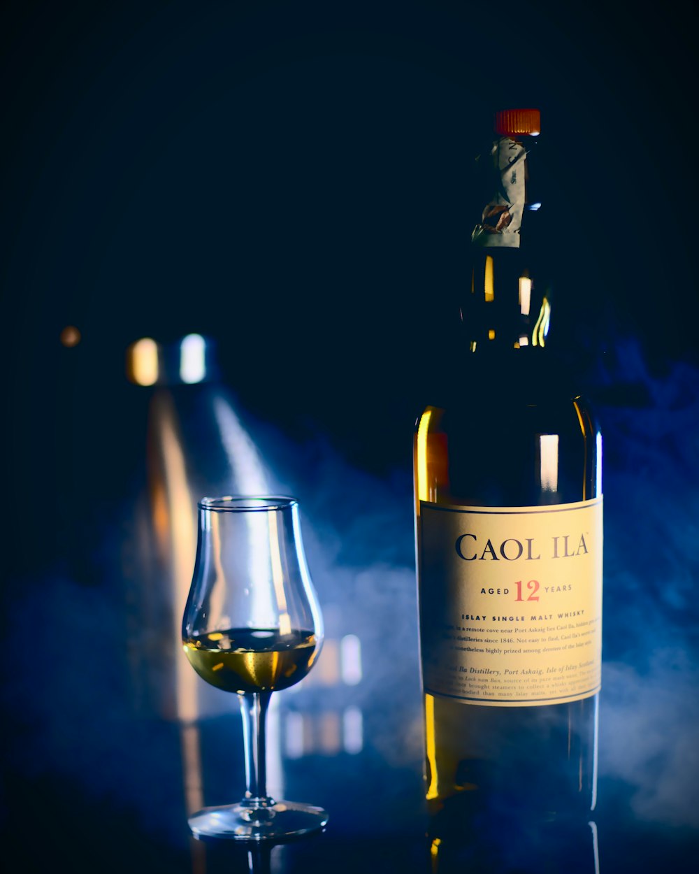 와인 잔 근처의 Caol Ila 병