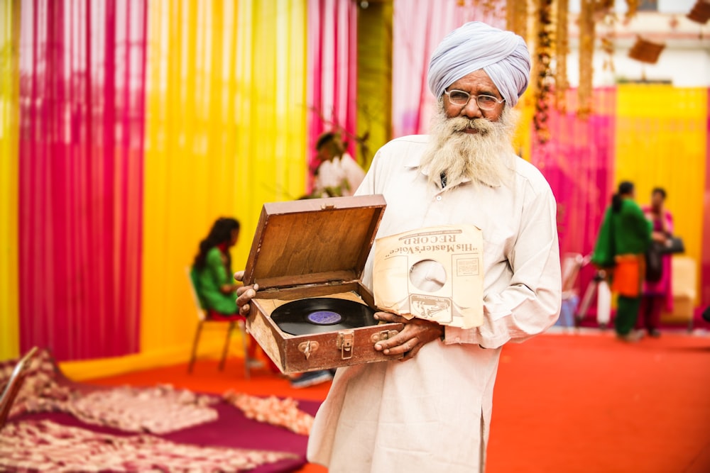 hombre de blanco thobe sosteniendo un reproductor de vinilo