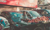 An apple vendor by parked cars