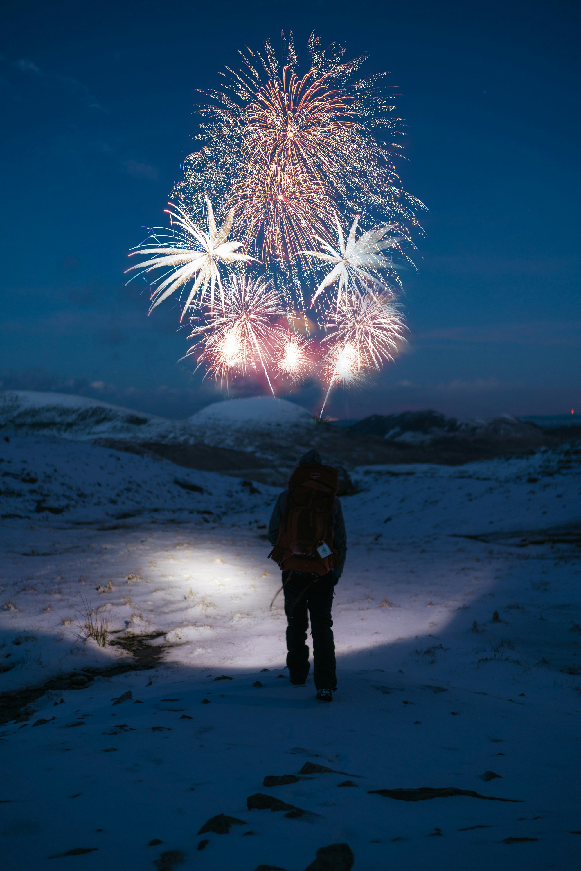 silhouette of person facing fireworks at nightime