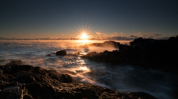 photo of body of water and boulder during daytime