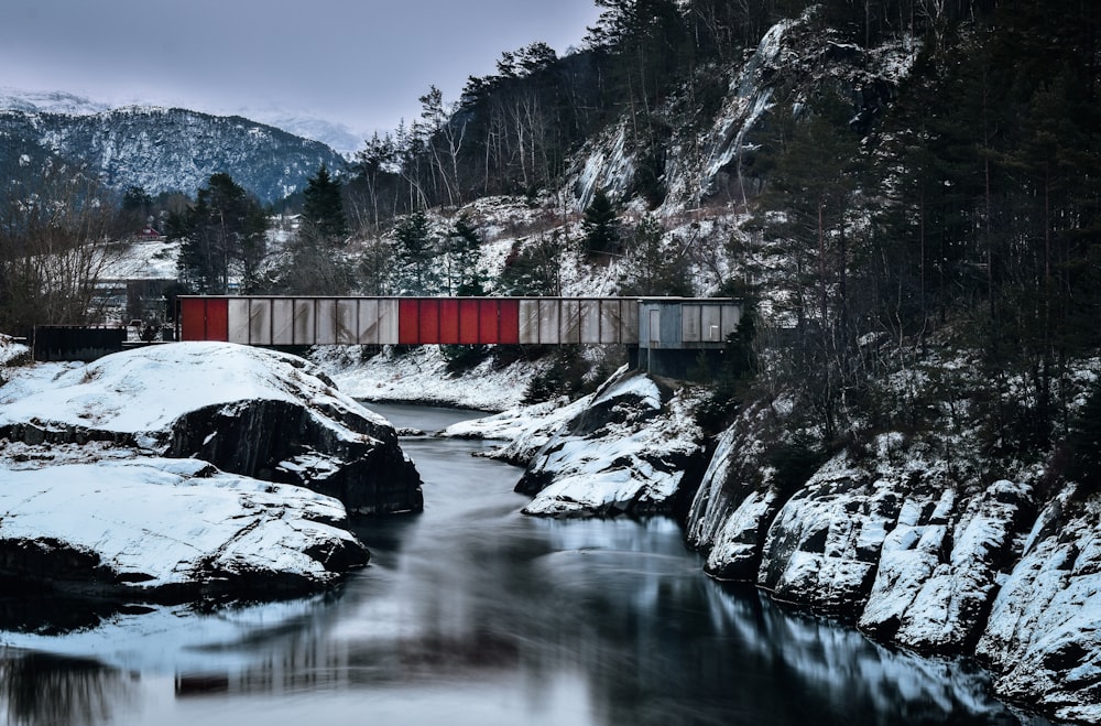 body of water between snow-covered rocks during daytime