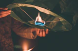 Close-up of artisan hands crafting delicate paper lanterns by soft warm light near the water.