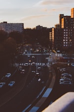 A city street with a car driving during sunset.