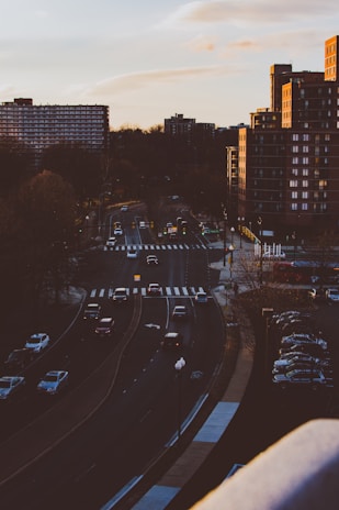 A city street with a car driving during sunset.