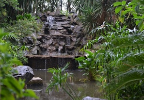 A tranquil garden scene featuring a small waterfall cascading into a pond.