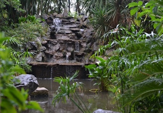 A tranquil garden scene featuring a small waterfall cascading into a pond.