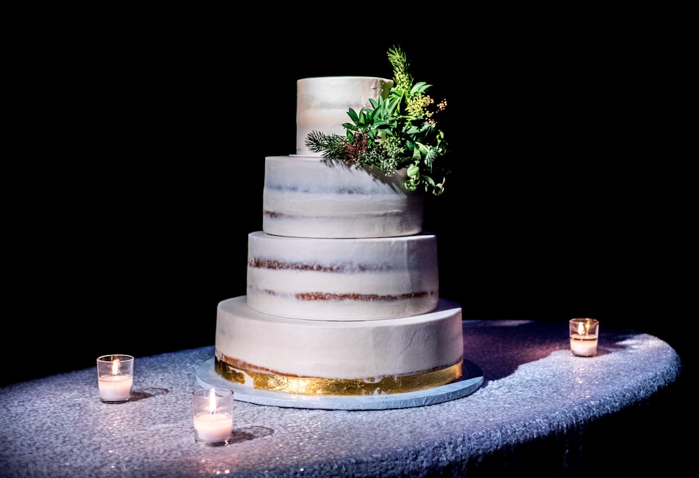 Gâteau à 4 étages sur le dessus d’une table grise avec trois bougies votives