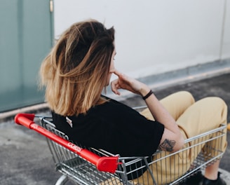 woman sitting on shopping cart near the wall