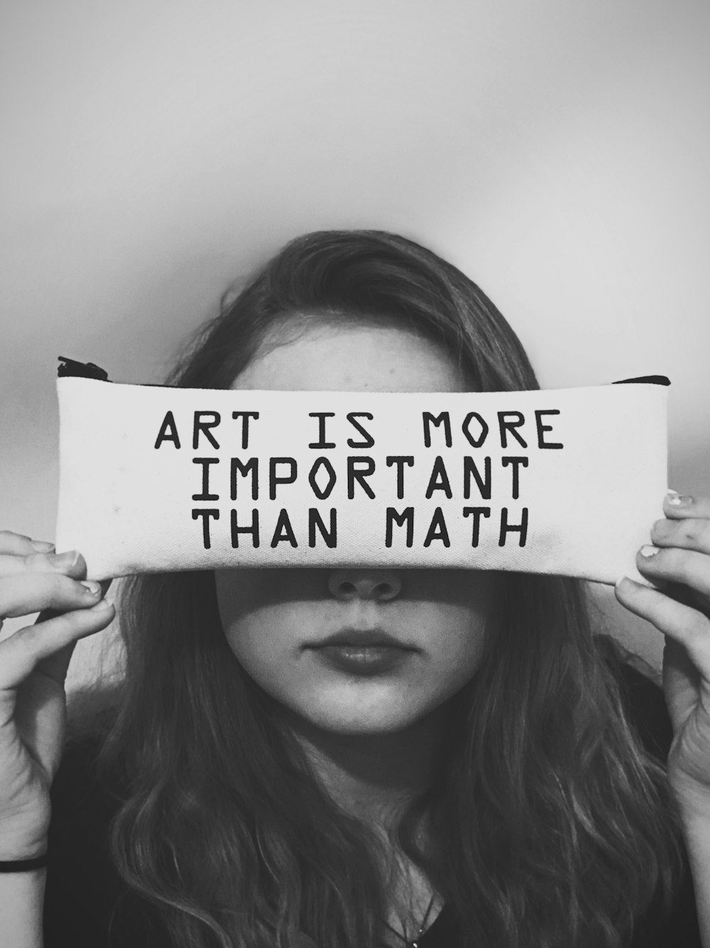 uma mulher segurando uma placa que diz que a arte é mais importante do que a matemática
