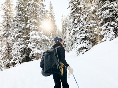 person standing near snow-covered forest mayflower teams background