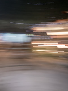 Blurred lights create streaks and lines against a dark background, suggesting motion or transformation. The colors blend into a swirl without clear definition of shapes or boundaries.