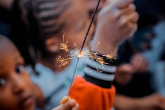 person holding sparkler beside boy