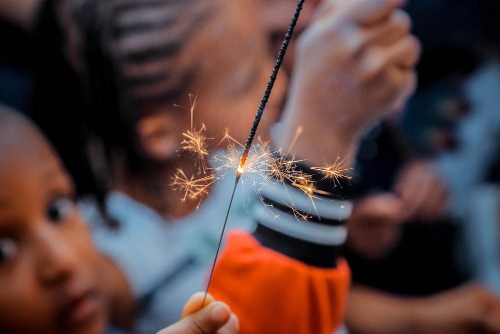 person holding sparkler beside boy