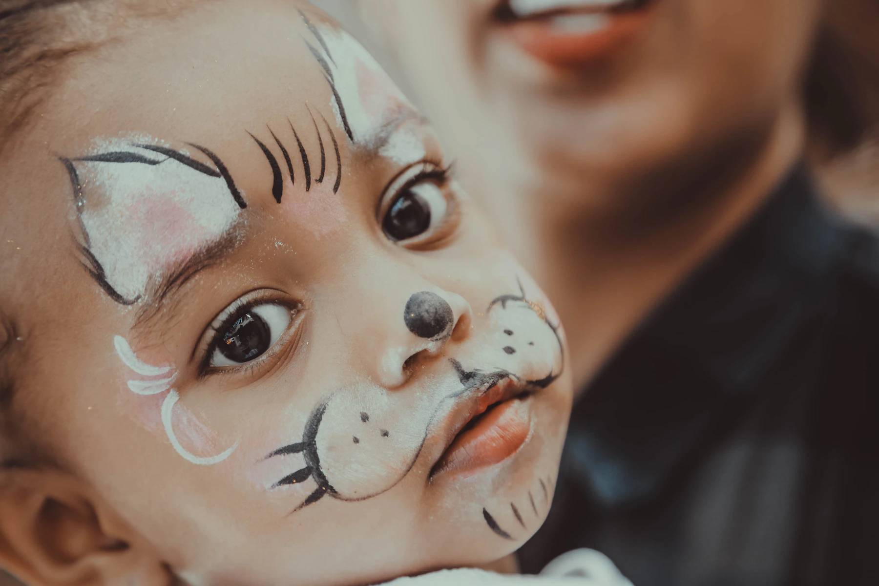 Enfant avec un maquillage artistique délicat, plein de joie.