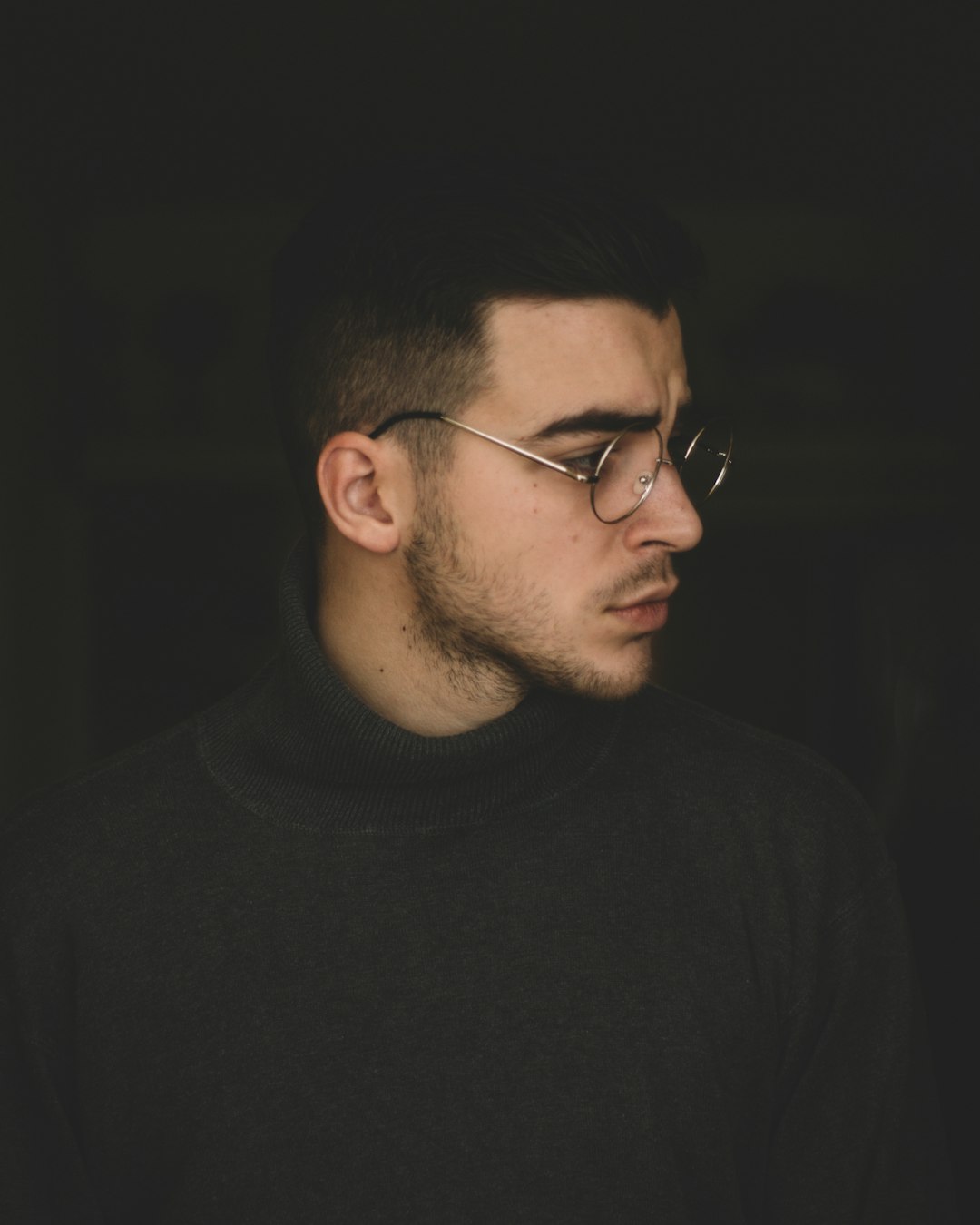 man wearing black turtleneck top and silver framed eyeglasses