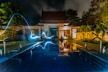 reflection of blue light crossing above pool near house during nighttime