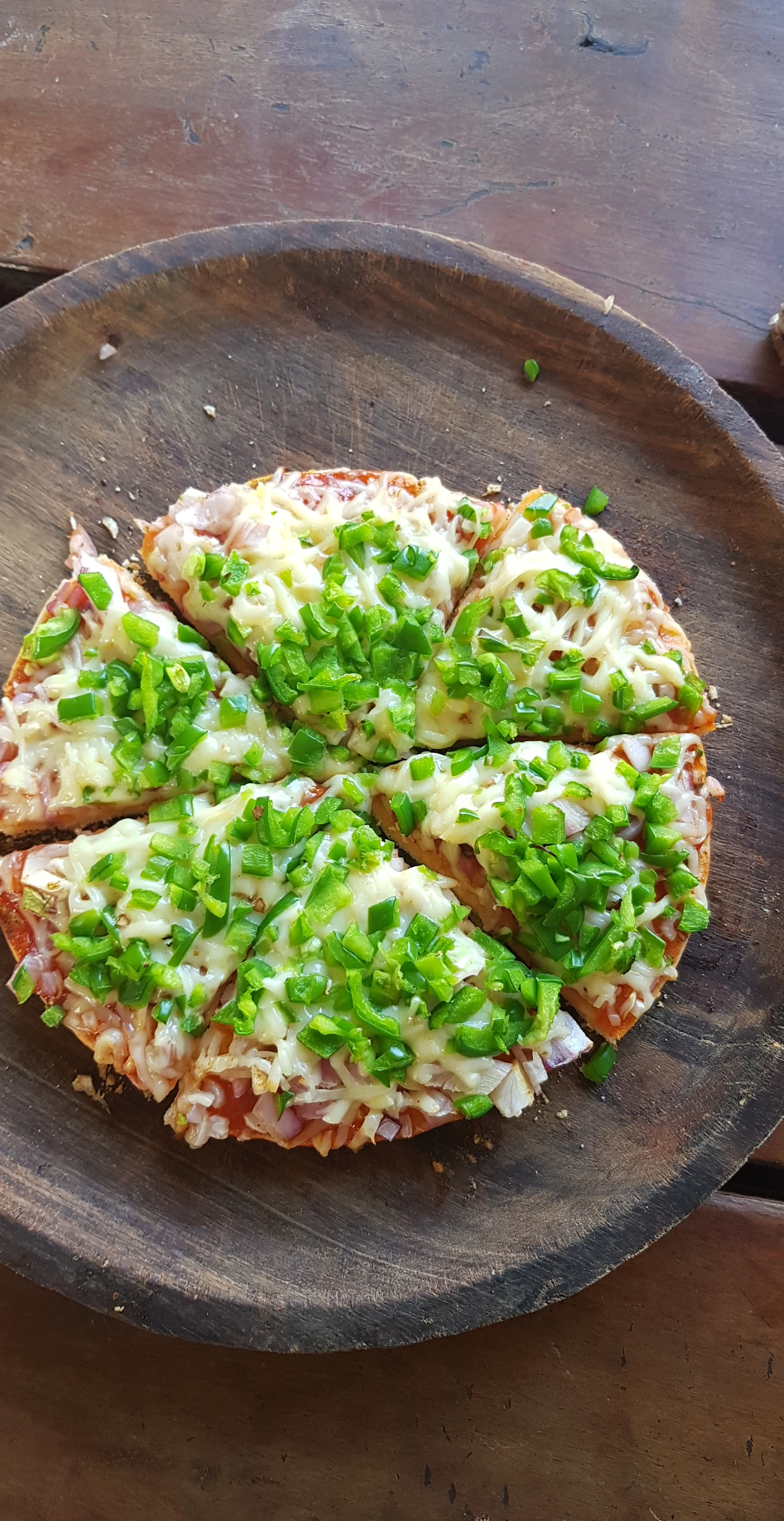 A vibrant, cheesy pizza topped with colorful bell peppers, olives, and melted mozzarella, served on a checkered tablecloth.