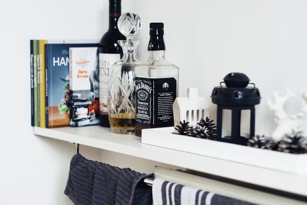 books beside decanter beside Jack Daniel's whisky bottle on wooden shelf