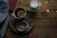 A cozy cup of herbal tea beside a softly glowing candle on a wooden table.