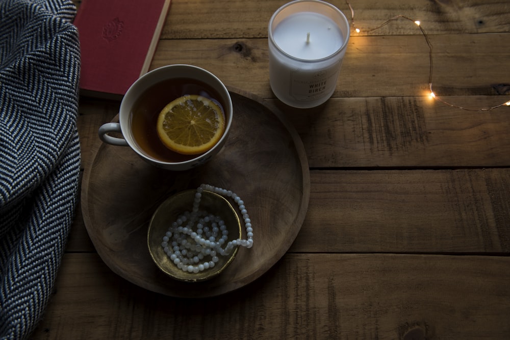 ceramic mug on wood tray near candle