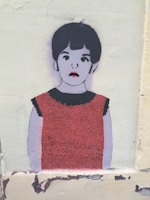 A stylized graffiti or stencil art of a young child, depicted with a minimalist face and short dark hair. The child is wearing a red dress with a black collar, and the background is a textured, light-colored wall.