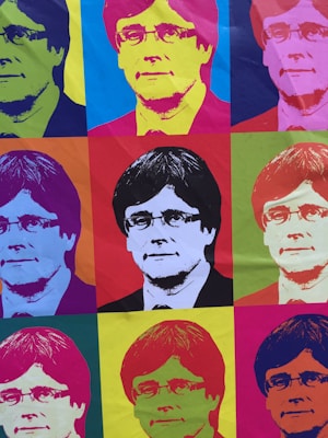 The image consists of a grid of nine portraits of the same person, each rendered in a style reminiscent of pop art. The portraits feature vibrant, contrasting colors with the subject positioned in the center of each section. The overall composition is colorful and visually striking, showcasing a variety of hues in each individual square.