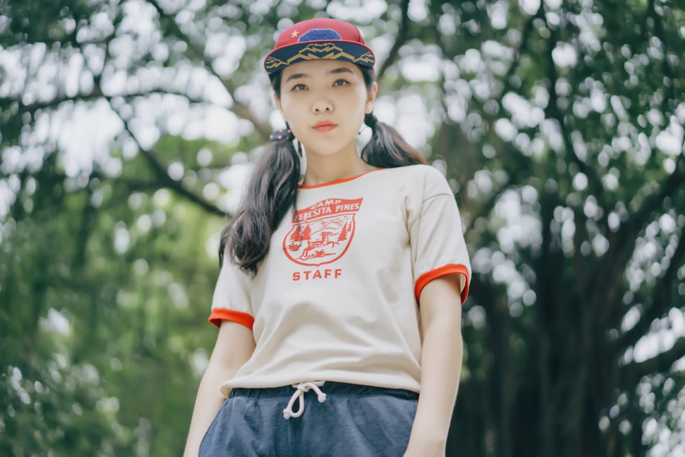 woman wearing white and orange shirt standing near tree