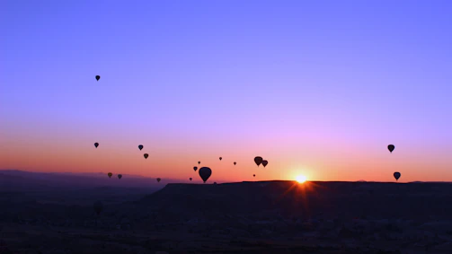 A colorful hot air balloon floating gently over a peaceful countryside at sunrise.