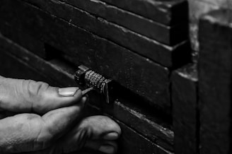 A close-up of hands manipulating a combination lock embedded in a textured, rugged surface, possibly a safe or chest.
