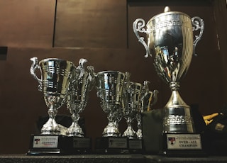 several silver and gold trophies on wooden surface