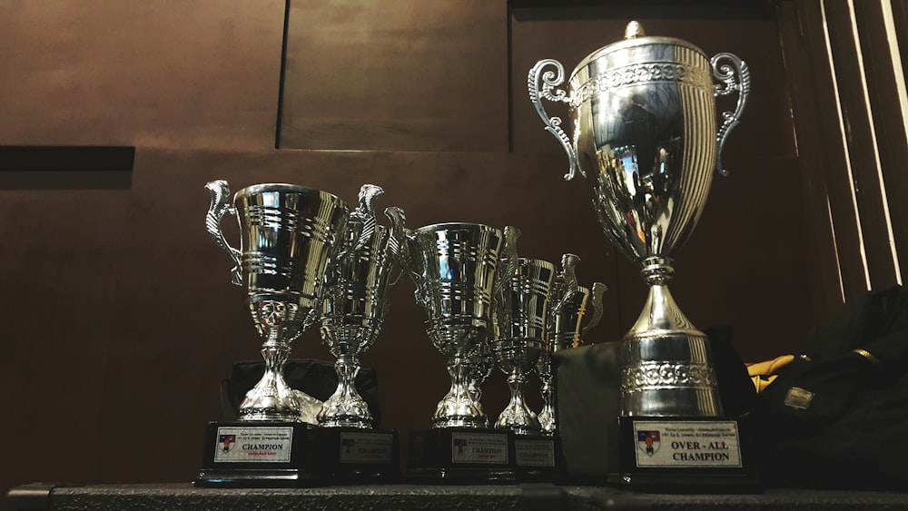 plusieurs trophées d’argent et d’or sur une surface en bois